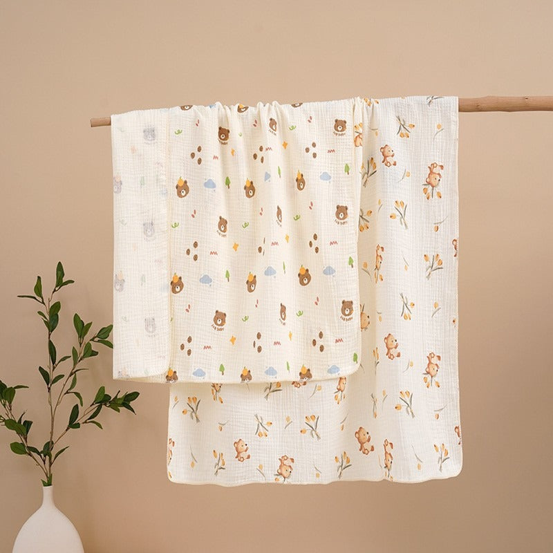 Two baby blankets with bear patterns hanging on a rod against a beige wall.
